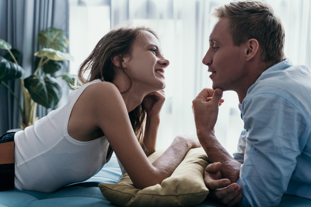 Beautiful young couple bonding and smiling while lying in the bedroom