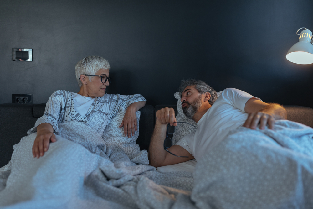 A relaxed senior couple lying in bed together at home during the morning hours