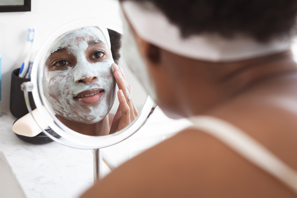 Mixed race woman spending time at home self isolating and social distancing in quarantine lockdown during coronavirus covid 19 epidemic, taking care of her skin in her bathroom.
