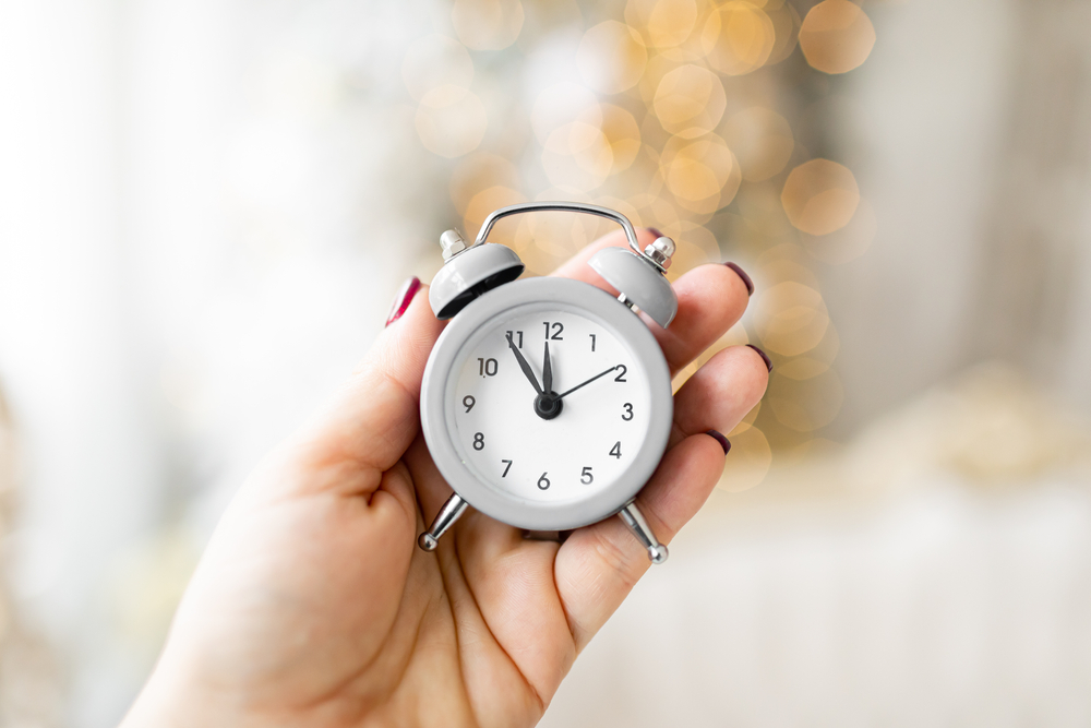 Alarm showing 11:55. Five minutes to New Year.  Christmas lights on back plane.