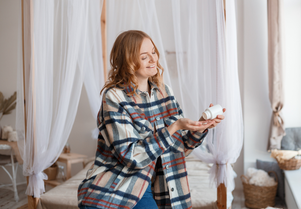 Woman Taking Medicine. Beautiful blond girl taking Medication, Holding Bottle With Pills In Hand. Diet. Nutrition. Healthy Eating, Lifestyle. Headache