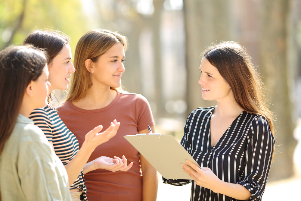 A happy woman checks three people on the street on a sunny day