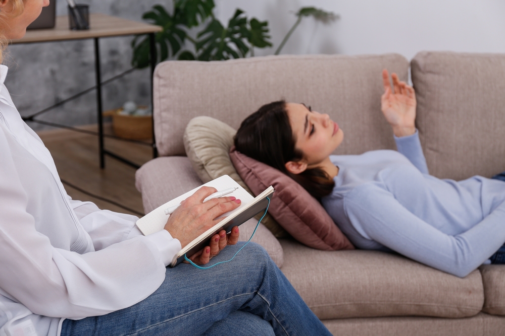 A grieving young woman in a psychotherapy session. A conversation between a psychiatrist and his client in the office. Copy space, background.