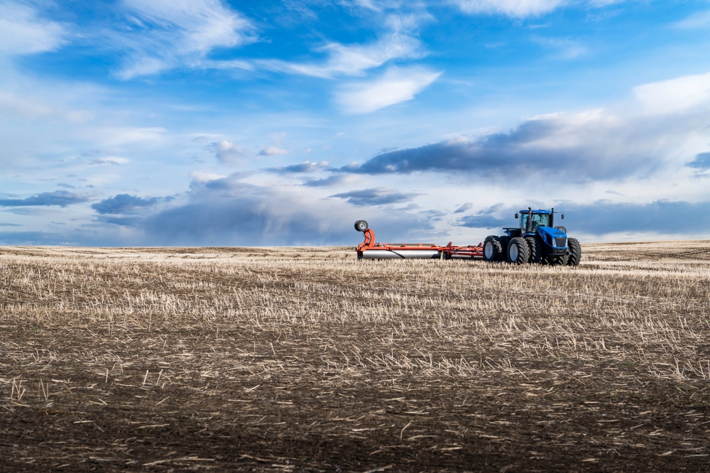 The eight-wheel tractor dragged in the stalks with rolling hills at Rocky Rocky View County Alberta Alberta Albanada under surprise skies.