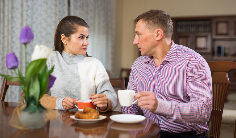 Family couple spending time together at home, talking over breakfast..