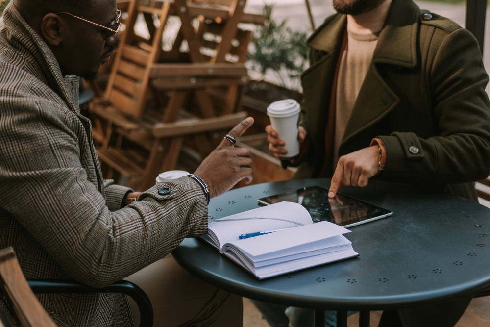 Black businessman stopped his white partner talking while he was pointing at the tablet and explaining something