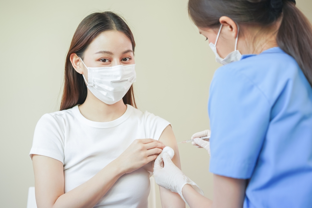 Covil-19 The hand of a young woman nurse, a doctor giving a sera vaccine, a shot of an Asian arm patient. Vaccination, Vaccination or Prevention of Diseases Against influenza or pandemic virus.