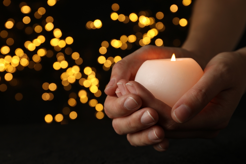 Mourning candles in hands, on a dark background.
