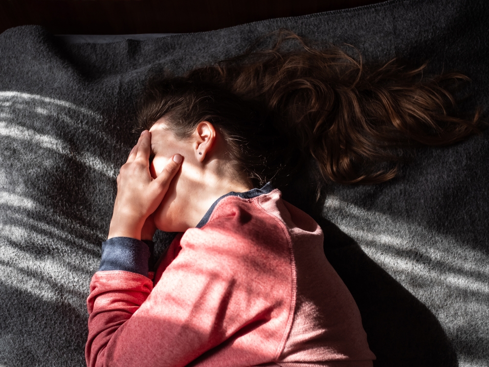 Stressed tired exhausted millennial woman on bed eyes closed suffers from headache.Mental health Psychology Low self-esteem Stress Mindfulness Anxiety Depression Emotional burnout Traumatic experience