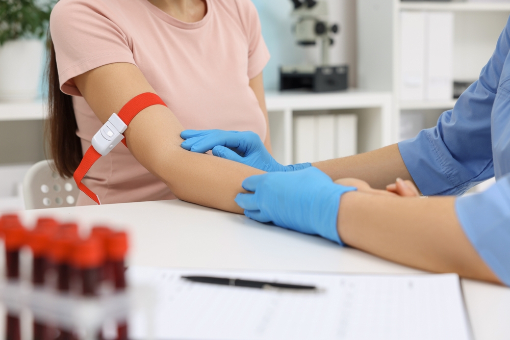 Lab tests. A doctor takes a blood sample from a patient on a white table in a hospital, nearby