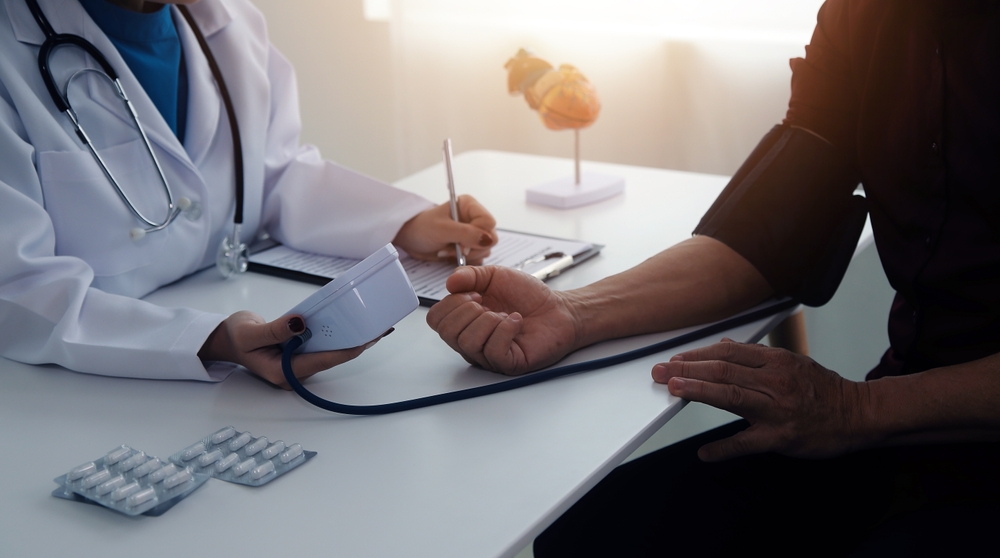 Doctor using sphygmomanometer with stethoscope checking blood pressure to a patient in the hospital.