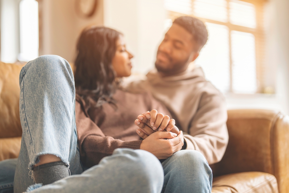 Couple Holding Hands on Couch in Living Room