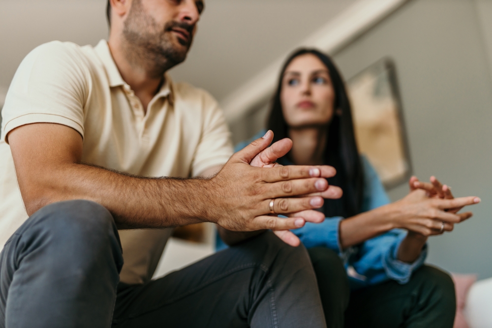 Smiling couple sitting on the couch trying to solve the problems at home in the living room