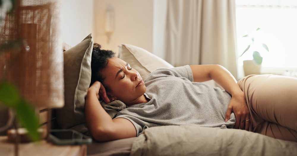 The woman, time and painful stomach in the bed of menstruation, digestion and endometriosis with cramples. A woman, stomach and hemorrhoids at home to be wrapped, bloom and colon distraction