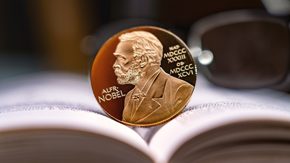 Moscow December 03 2024. Alfred Nobel's image on gold coin on physics book and reading glasses in background. Nobel Prize award. Nobel Prize for Literature concept.