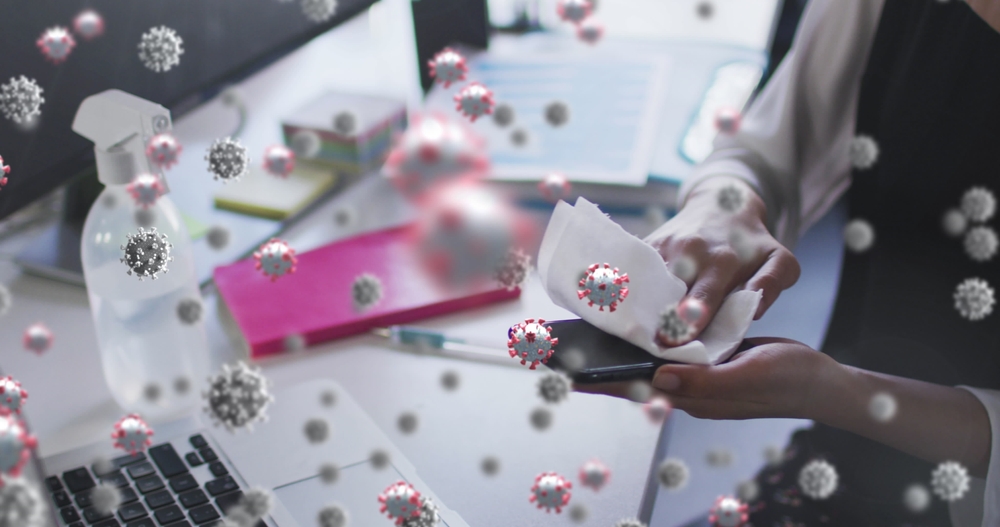 Images of a Covid 19 cell floating on a smartphone wiping the smartphone in the office. Place and place and business in the time of Covid 19 A digitally produced digital concept.