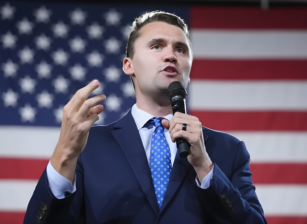 Charlie Kirk talks in front of the USA flag, American politician