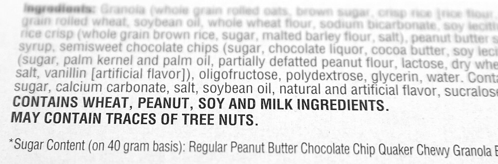 Ingredient list from a granola bar package showing allergen warning. Contains wheat, peanuts, soy, and milk ingredients. May contain traces of tree nuts.
