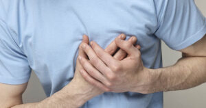 person with hands clasped over chest. Heart health concept