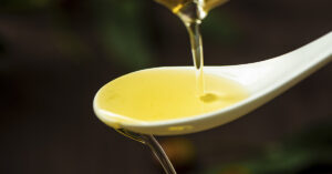 Why This Oil is the New Low Saturated Fat Alternative to Olive Oil cooking oil being poured onto white spoon