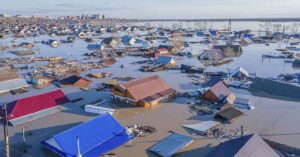 flooded area, with people navigating the water and debris, likely the aftermath of a natural disaster.