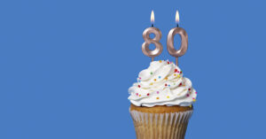 Cupcake with number 80 candle on top.