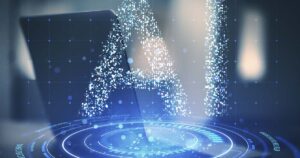 The letters 'AI' (for Artificial Intelligence) formed by bright, shimmering digital particles, overlaid on a dark, blurred background with a laptop and a blue circular holographic interface/grid.