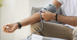 man putting on a blood pressure cuff to measure blood pressure, also known as a sphygmomanometer