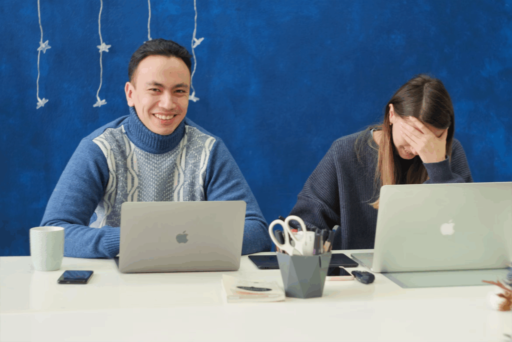 two people at an office with laptops on desk