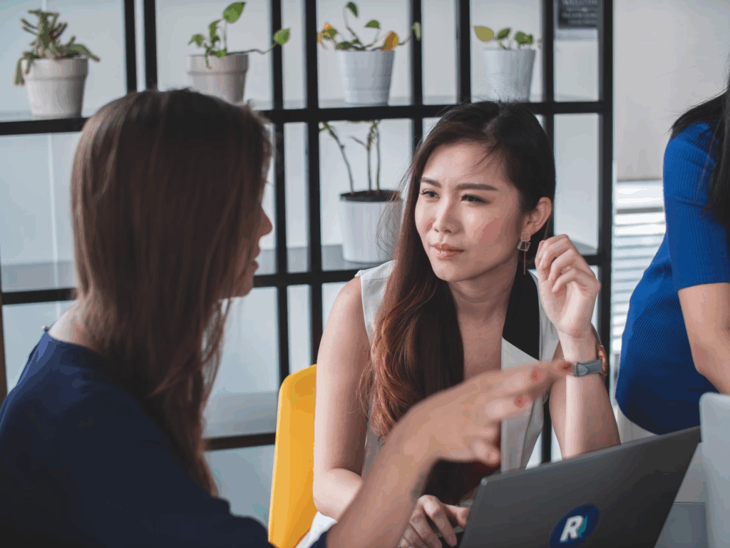 woman sitting across from other woman at table with laptop