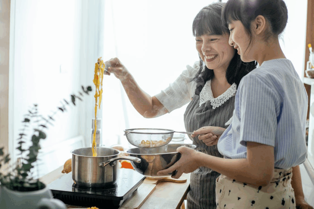 Loving mother and teen girl making pasta