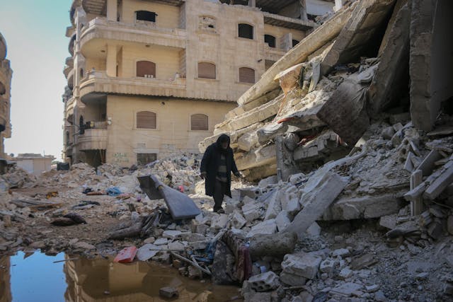woman walking down street of rubble