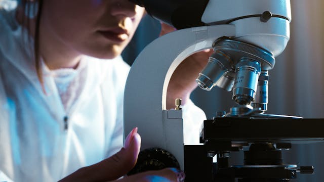 researcher looking through microscope