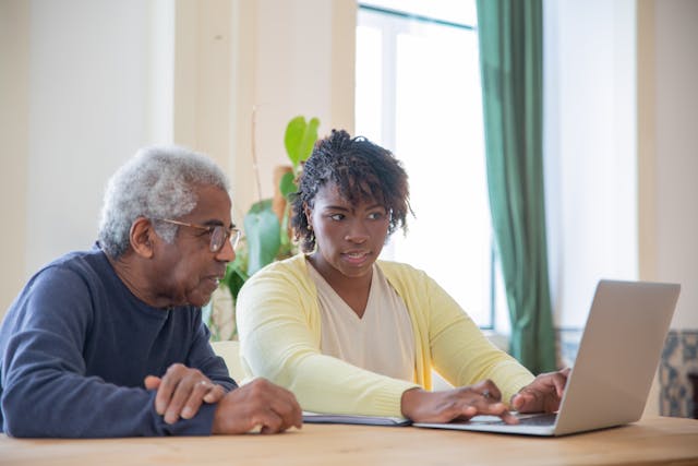 two people sitting by a laptop