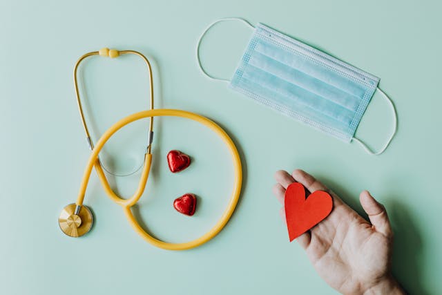 hand holding a paper heart and stethoscope. 