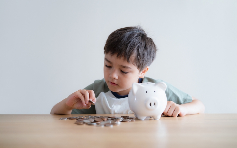 Child boy putting coins into piggy bank, Child counting saving money, Young kid holding coin on his hands, Children learning financial responsibility and planning about saving money for future