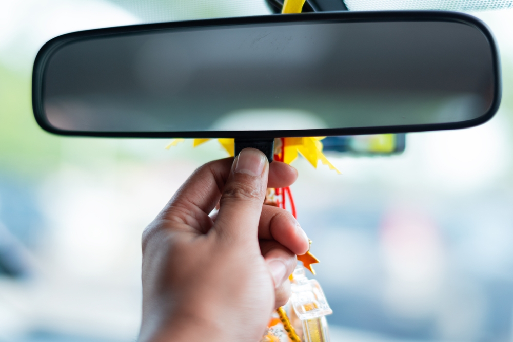 Man's hand presses adjusting rearview mirror dimming. Selective focus.