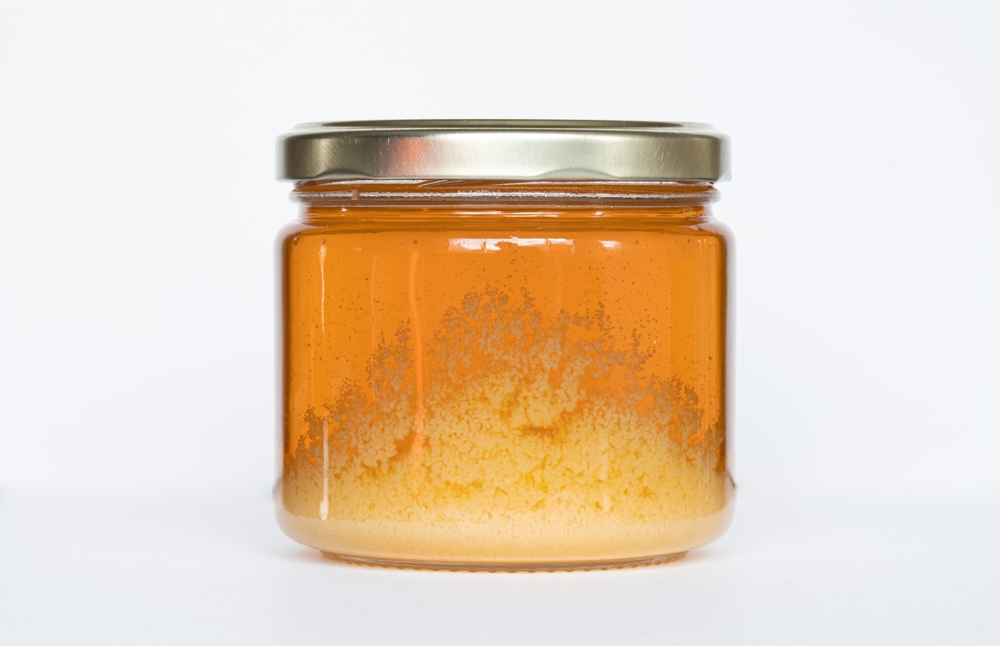 A jar of honey that begins to cry with a white background