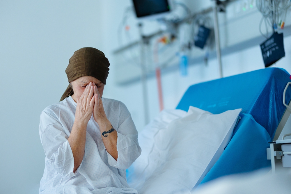 Senior woman sitting in hospital room after chemotherapy.