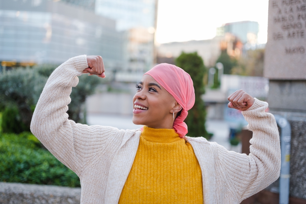 Young woman in pink scarf fights cancer disease and feels strong to overcome it. Concept: disease, fight, health care
