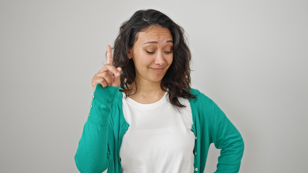 Young beautiful hispanic woman saying no with finger over isolated white background