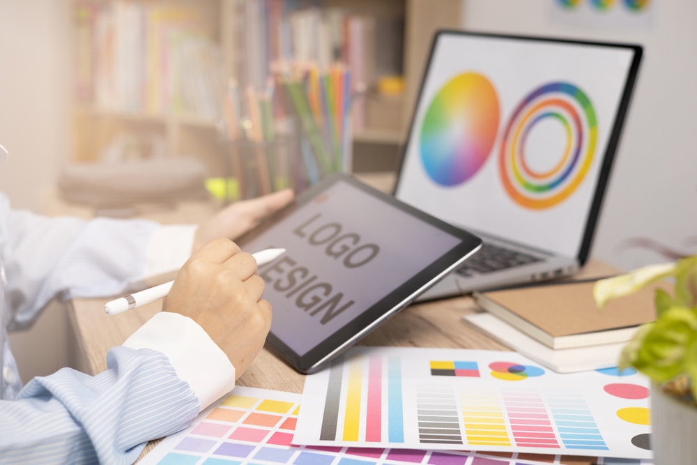 Designer creating graphic logo on a table using tablet and laptop