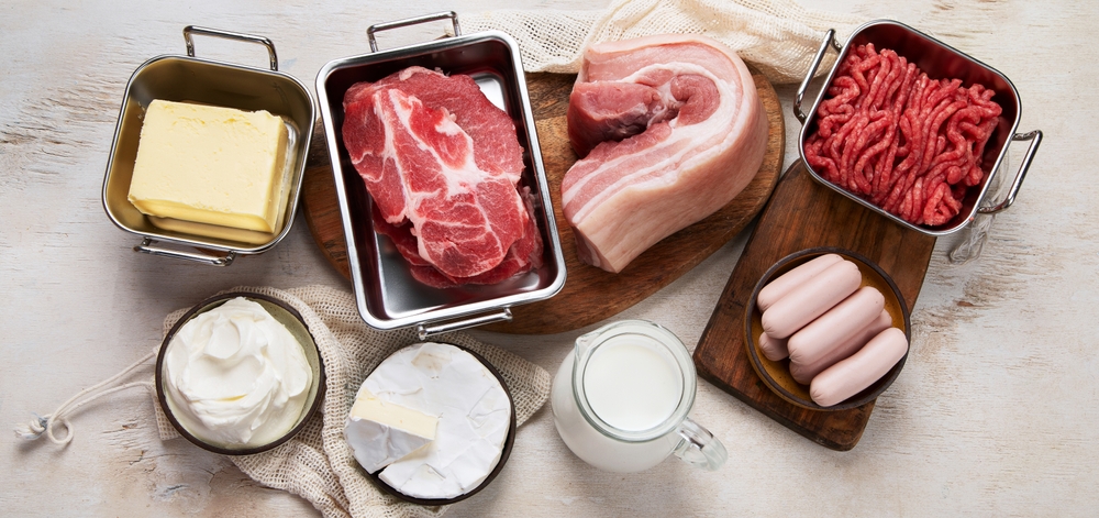 Saturated fats on tables. Raw meat, sausages, cheese, butter. Bad food concept. Top view, copy space.