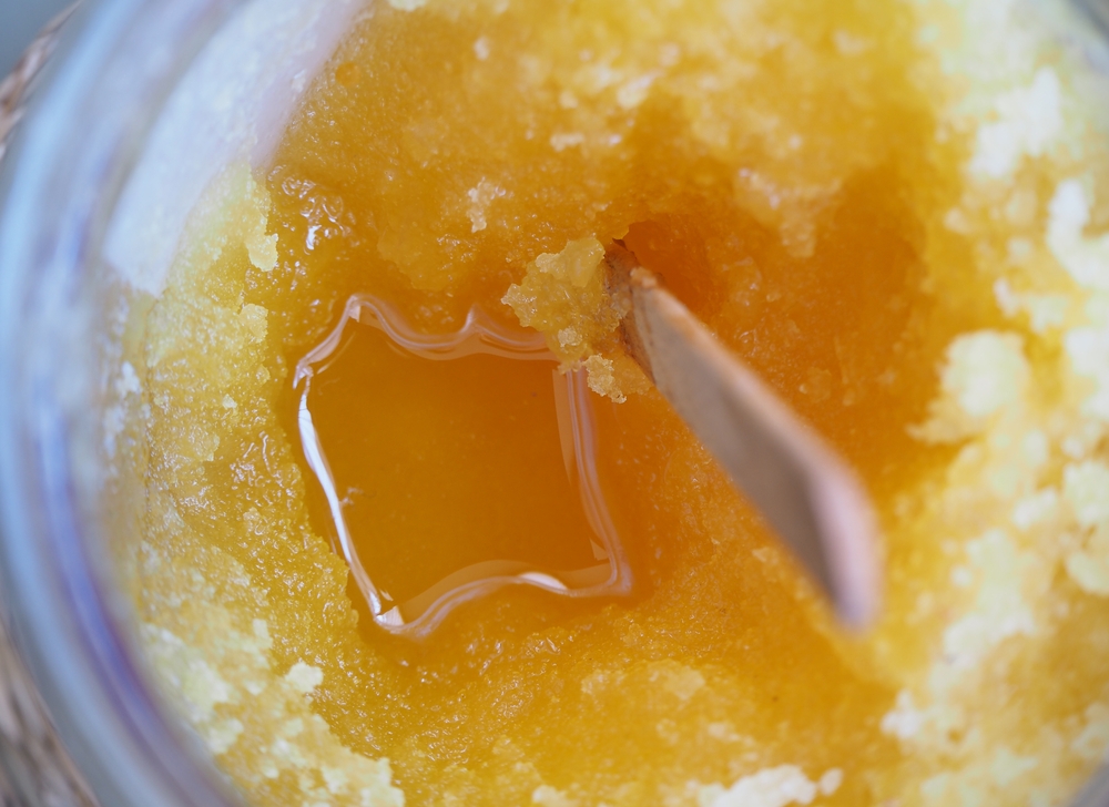 Honey and a wooden stick in a glass jar. Selective focus.