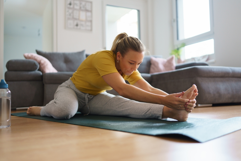 Woman exercising at home, stretching her body. Solo home workout and meditation, morning or evening workout routine.