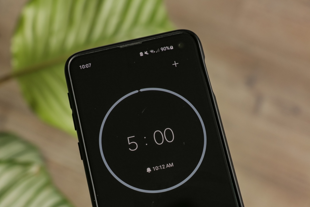 A phone with a black and white 5-minute timer to study with the pomodoro method on a blurry background. Perfect for students planning their time studying, doing homework, being productive.