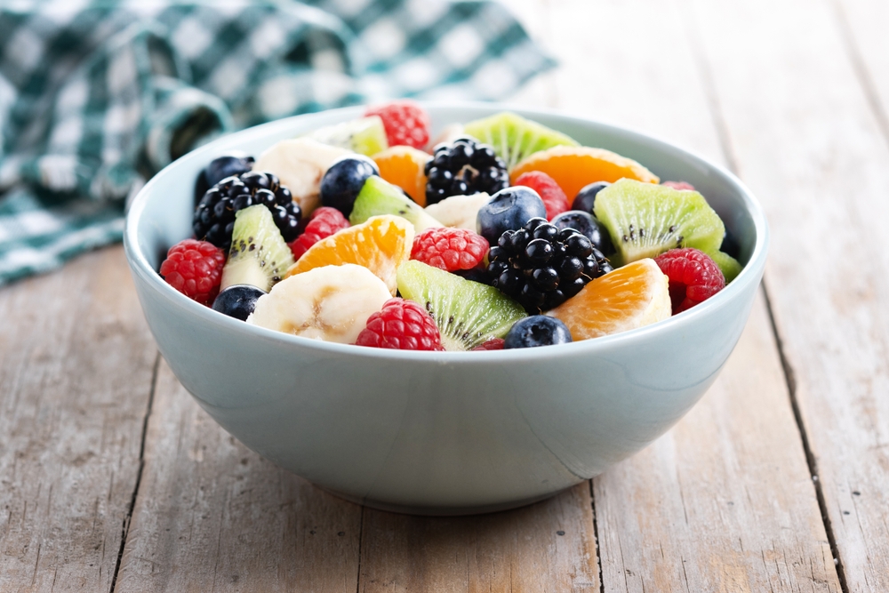 Fruit salad in a blue bowl on wooden table