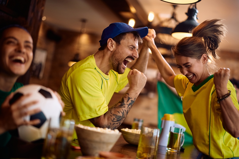 Happy sports fans having fun and celebrating while watching a game in bar. 