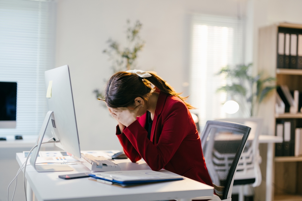 Young businesswoman is suffering from burnout syndrome, feeling stressed and overwhelmed while working on a deadline in the office