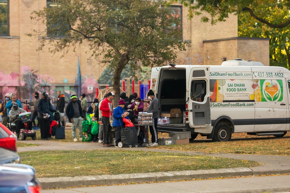 Toronto, Canada _ Oct., 26, 2024: People line up for food supplies from a mobile foodbank at a park in downtown Toronto. Food insecurity has become a major issue in the country's largest city.